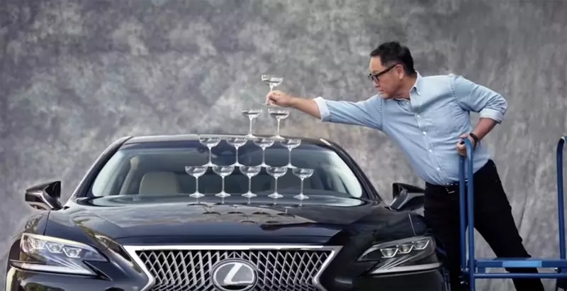 Toyota Motor Corporation President Akio Toyoda reproduces an advertisement for a 1989 Lexus LS champagne glass.